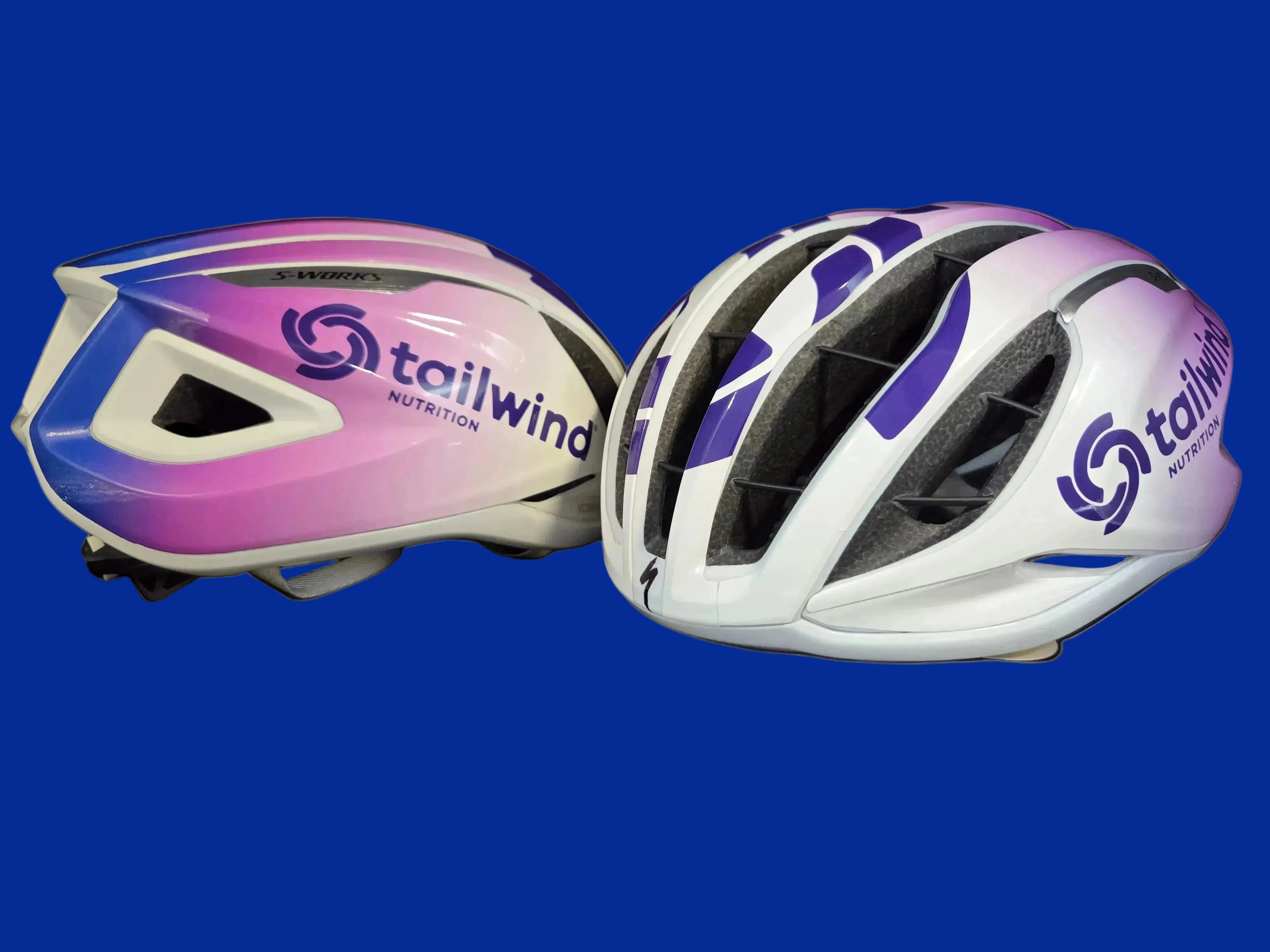 Two bicycle helmets with Tailwind Nutrition branding on a black background